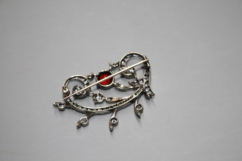 An early 20th century yellow and white metal, red spinel and diamond set foliate scroll brooch,